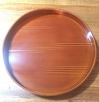 Top view of the round orange lacquer tray with fine gold linear details.