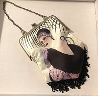 Photo showing flapper girl design, silver metal frame and chain, black fringe tassels