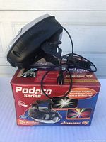 Side view of the Pod250 Series 250w Moonflower lighting projector showing its black casing and attached power cord sitting on the box.