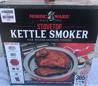 Close-up of Nordic Ware stovetop kettle smoker box showing included items and usage information.