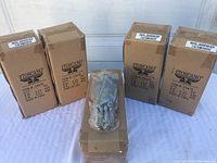 Five cardboard boxes labeled Toscano containing hanging vampire bat decorations, displayed with one bat visible wrapped in plastic on top of a box