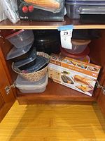 Shelf with Copper Chef Bake & Crisp Pan set box and multiple plastic storage containers of various sizes and colors.