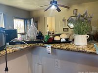 Wide angle photo of countertop with vases, faux flowers, black tray holding stones and candle holders.