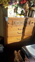 Front view showing three drawers, carved top drawer front and metal hardware