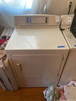 Front view of the white GE Profile gas dryer showing the door, handle, and top control panel with buttons for settings.