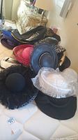 Pile of multiple hats showing leather cap, sequin-trimmed hat and others