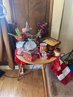 Photo of the full assortment including two candy jars, silk flowers, wicker basket, butter jug, ceramic container, and crystal eagle figurine arranged on a small table