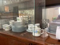 Mikasa Brook Hills china pieces including stacked plates and teapot in cabinet