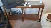 Full view of the wooden sofa table showing glass top, cane shelf, and scratches on wood.