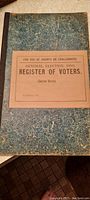 Front cover of 1893 General Election Register of Voters log book showing marbled blue-green pattern and label with printed title and instructions.