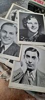 Close view of several black-and-white 8 x 10 inch movie star still photographs showing headshots of actors Errol Flynn, Priscilla Lane, Eddie Cantor, and others from the 1930s.