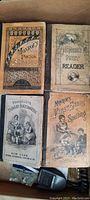 Four small sized hardcover books from late 1800s school readers and teaching collection, showing detailed front covers with illustrated figures and decorative typeface.