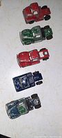 Five antique metal toy truck cabs arranged vertically showing tops and sides, highlighting wear and paint condition.