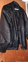 Front view of men's black leather jacket showing zipper front, elasticized cuffs and waist, and smooth leather body.