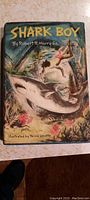 Front cover of Shark Boy hardcover book showing vibrant illustrated dust jacket with boys and shark in action scene.