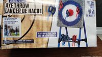 Box front showing the Ultimate Axe Throw branding and image of assembled axe throwing target with axes embedded in bullseye, with height noted as 152 cm (5 ft) tall and heavy duty steel base.