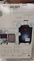 Photo of the back of packaging box showing the Delsey Paris branding and suitcase features