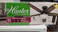 Front of sealed box showing Hunter logo, 52-inch Brenham Designer Series fan image, model, and size info