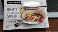Box for Tramontina branded enameled cast iron skillets with image of food cooked inside skillet, listing 2 piece set.
