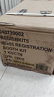 Side view of the cardboard box packaging showing the lot label and markings: REGISBKIT5 5x05 REGISTRATION BOOTH KIT, weight markings, and Made in China.