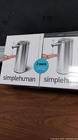 Photo showing front of two identical Simplehuman touch-free sensor soap dispenser boxes, indicating a 2-pack.