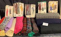 Photo of fabric rolls including wool, suiting, linens, and silk with vintage Vogue and McCall's sewing patterns displayed on top to show variety and condition.