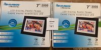 Two boxed Panimage 7" LED digital photo frames side by side, showing front of boxes with model details and photos.