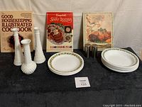 Photo of the full lot including 3 milk glass vases, Corelle plates and bowls with floral patterns, 3 cookbooks and stainless steel salt and pepper shakers.