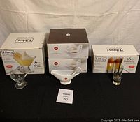 Boxes and several pieces displayed of glass dessert bowls, ceramic sauce boats, and glass parfait dishes with spoons, all in original packaging.