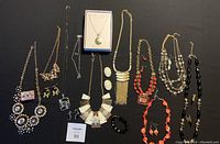 Full view of all 8 assorted bold costume jewelry sets including necklaces with matching earrings displayed on black background.