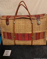 Front view of large vintage woven picnic basket showing straw construction, red woven stripes, leather handles and straps with metal latch closures