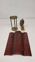 Photo showing folding bamboo screen with carved Chinese characters, brass stand with twisted legs, and brass eagle figurine