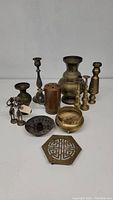 Group lot of brass decorative items on white background showing candlesticks, bowls, figurines, and other metal objects.