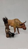 Photo of group lot showing carved water buffalo, African wooden statue with black hair, and a small bird figurine in front.