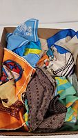 Photo of a box with multiple colorful ladies scarves, showing various patterns and fabrics indicating silk materials.