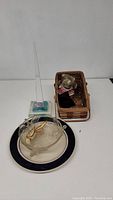 Full view of group lot showing resin obelisk, glass bowl with bird, ceramic plate, and small stuffed toy in basket.