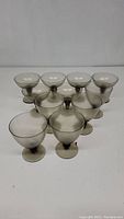Ten smokey glass stemware pieces of two distinct styles arranged in group.