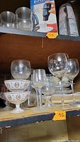 Photo showing an assortment of clear glass stemmed wine glasses and two ceramic footed bowls with decorative floral and medallion designs.