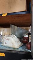 Frosted glass serving bowl and ceramic covered cheese plate with floral pattern on a shelf with other items