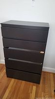 Front view of the dark brown 5-drawer dresser with one drawer partially open showing extra pieces inside.