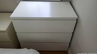 Front view of white formica dresser showing three drawers.