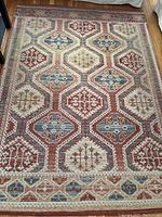 Full view of area rug laid flat on wooden floor showing pattern and condition.