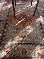 Full view of the rug showing pattern and a table leg on it, revealing size and style.
