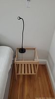 Side table with glass top and black gooseneck lamp seen from one angle