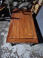 Top view of rectangular wooden tabletop showing scratches and wood grain texture.
