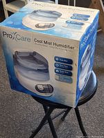 Box of ProCare Cool Mist Humidifier showing front and side with product image and features.
