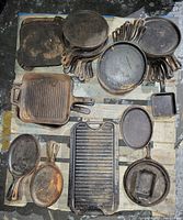 Overhead view of pallet with assorted cast iron cookware including skillets, griddle and bakeware.