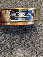 Side close-up photo of the brass sieve showing the metal label with measurements and mesh number.