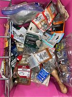 Various bags and packages of sheet metal screws in a pink container, including brands Everbilt and Mac Hardware, mixed with hand tools such as screwdrivers and wrenches.