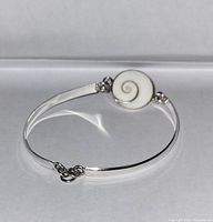 Front view showing the white enamel pendant with gray swirl and circular silver band with clasp.
